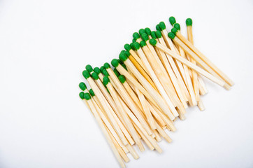 Wooden little matches with a green head. A bunch of matches are on the right. Left place for text. Macro