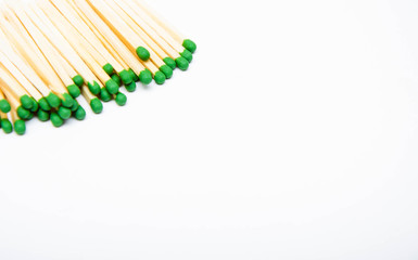 Wooden little matches with a green head. A bunch of matches lie on the left and in the upper left corner. Right place for text. Macro