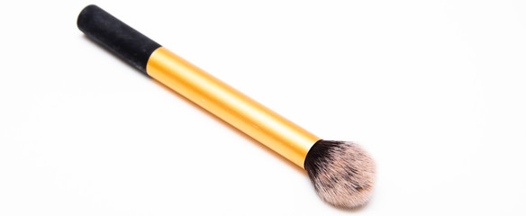 Large fluffy makeup brush with gold pen and black edge. The brush lies on a white background in macro