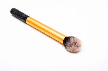 Large fluffy makeup brush with gold pen and black edge. The brush lies on a white background in macro