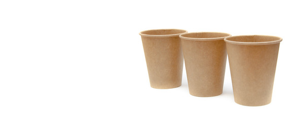 Brown paper cup for coffee, tea, a drink from environmental materials on a white background. Three glasses stand one after another diagonally. Glasses go far into perspective