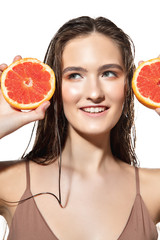 Happiness. Close up of beautiful young woman with grapefruit slices on white background. Concept of cosmetics, makeup, natural and eco treatment, skin care. Shiny and healthy skin, fashion, healthcare