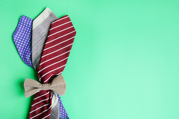 Happy Father's Day concept image with bouquet of man's ties and bowtie on green background. Copy space.