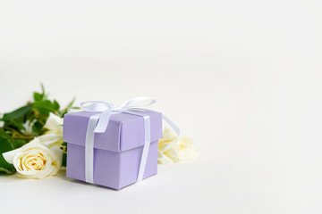 Roses and gift on light background with copy space, selective focus