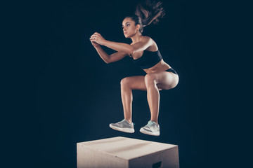 Portrait of her she nice attractive purposeful sportive strong muscular slim thin adorable lady working out jumping up on wooden box isolated over black background