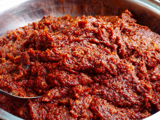 closeup Thai spicy chilli paste (mixture of red chilies, onion and garlic) texture with spoon in...