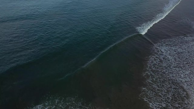 Aerial shot of empty beach with the waves crashing against the shoreline.
