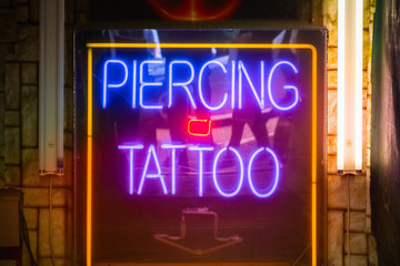 Neon sign piercing and tattoo on display at Camden market in London