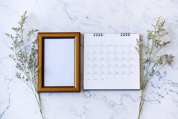 Picture frame and calendar and Caspia flower on marble background