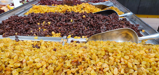 Green and brown raisins in boxes for sale at market background