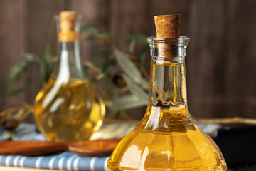 Olive oil bottle on wooden table, close up.
