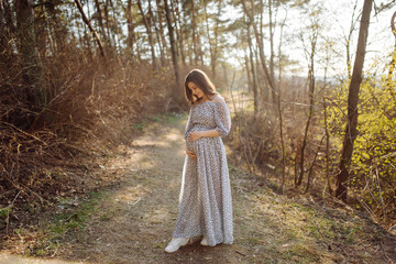 Young pregnant woman relaxing in park outdoors