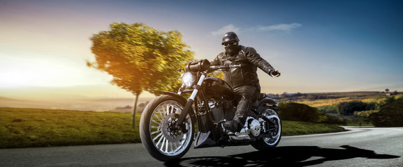 fat biker on a bobber motorcycle greeting while riding the empty road on a countryside