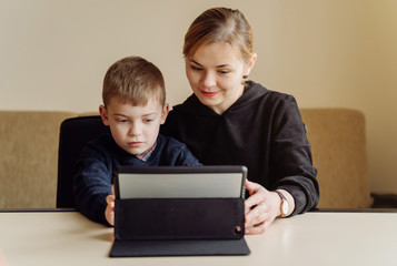 Mother using laptop and tablet teaching with her son online at home in his room