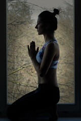 Silhouette of a young woman in yoga position
