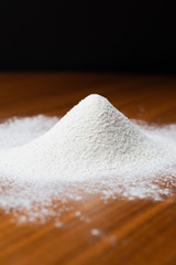 Scattered flour on a brown table with a black background.