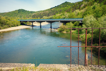 Fototapeta na wymiar View of a mountain valley with river and bridge in spring. View from destroyed bridge