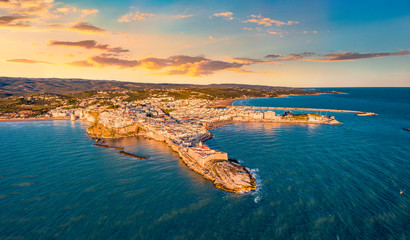 View from flying drone. Exciting evening cityscape of Vieste - coastal town in Gargano National Park with Castello Svevo, Italy, Europe. Breathtaking summer sunrise on Adriatic sea.