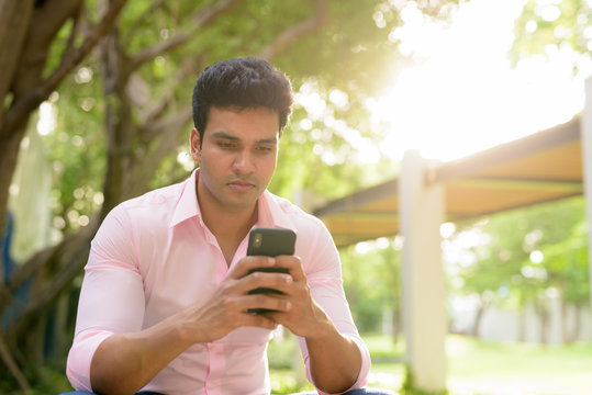 Young Handsome Indian Businessman Using Phone At The Park