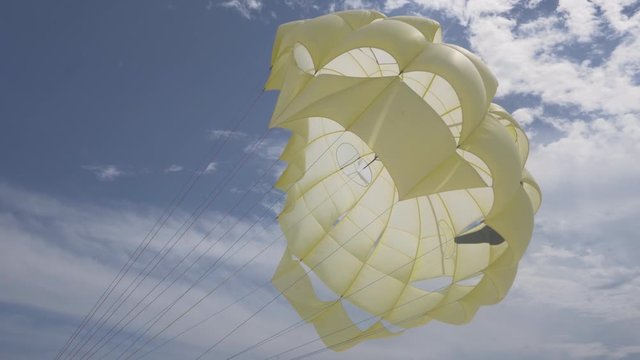 Parachute flying in wind with blue sky at Seaside. Yellow parachute opened in strong wind.