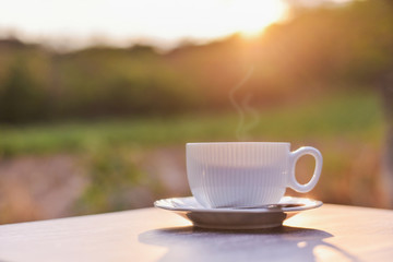 White hot coffee cup against the sunrise at the top of mountain background
