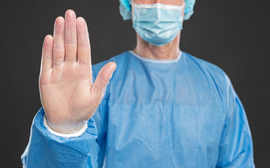 Doctor in protective uniform showing stop gesture