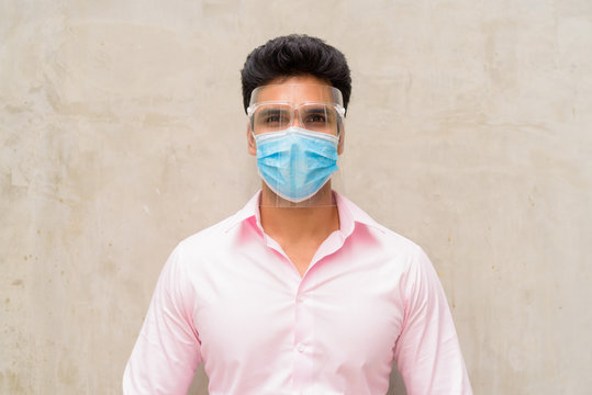 Young Indian Businessman Wearing Mask And Face Shield For Protection From Corona Virus Outbreak Outdoors
