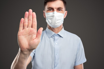 Man in medical mask showing stop gesture