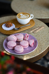 Macaroons on a plate on a gray background. French macarons isolated. Selective focus. Beautiful pink macaroons with coffee. Stylish arrangement sweet. Flat lay, top view. Macro photo.