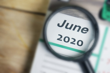 June 2020 Calender under magnifying glass. Selective focus.