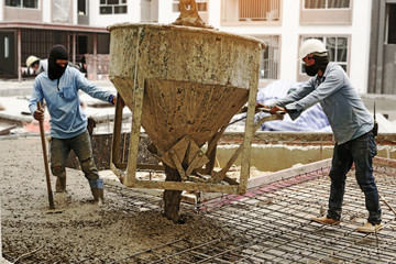 The men workers pouring concrete on the floor