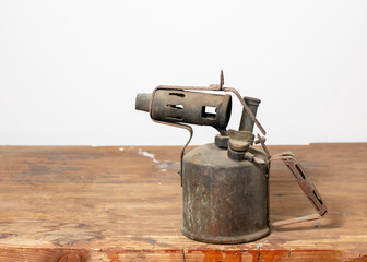 Old, rusty, antique blowlamp on a workbench