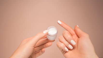Beautiful hands hold a jar of cream.