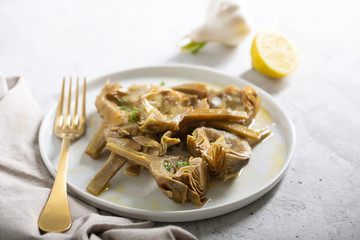 Cooked Italian Artichokes on the white plate with lemon