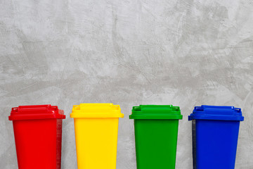 Red, Yellow, Green and Blue Recycle Bins. Concrete wall background. Copy space