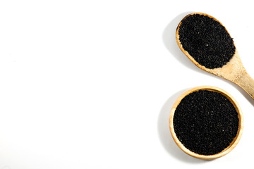 Heap of black sesame on wooden spoon . White background