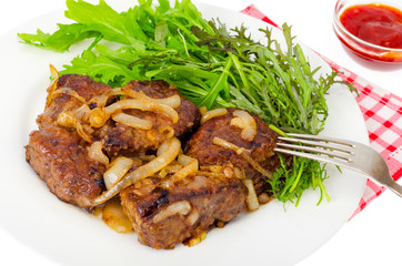 Pieces of fried liver with onions, fresh leaves of salads