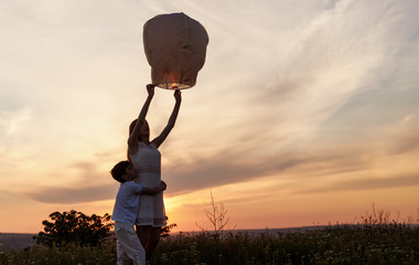 Brother and sister launching sky lantern - Powered by Adobe