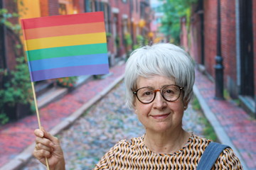 Senior woman holding rainbow flag outdoors