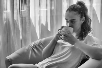 Woman sitting in her living room having a cup of coffee