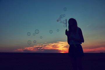 Cute woman blowing bubbles outdoors.