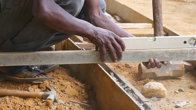Male indian hands checks levels for accuracy during building wooden floor. Unrecognizable local builder works on construction area. Concept of future project. Close up Slow motion