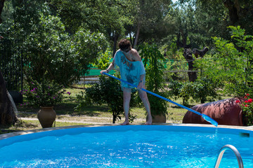 Woman cleaning the pool at her country house. Summer at home concept. Lifestyle