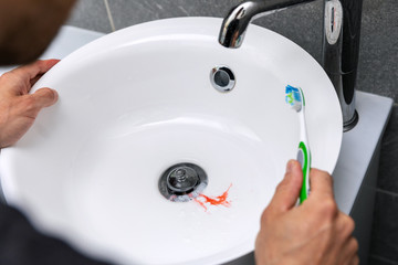 man have bleeding gums while brushing the teeth. tooth decay and gingvitis concept