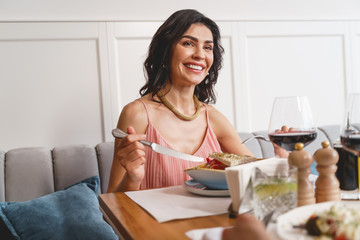 Obraz na płótnie Canvas Joyful young woman having dinner in restaurant