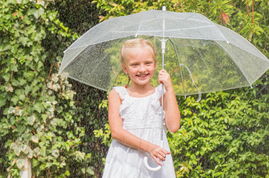Littel girl with umbrella playing in the rain.