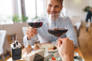 Young man and woman toasting with wine in restaurant