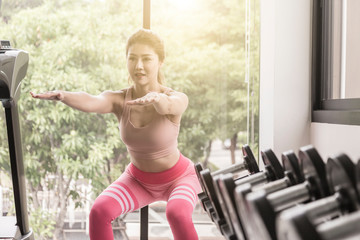 Squat down. Sporty fitness woman in sportswear exercising thigh muscle, doing squat workout at gym...