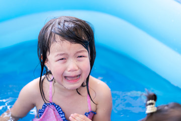 4-year-old Asian girl is crying in blue pool while playing in water and there is accident in water...