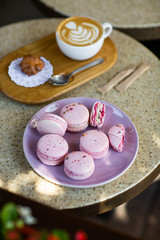 Macaroons on a plate on a gray background. French macarons isolated. Selective focus. Beautiful pink macaroons with coffee. Stylish arrangement sweet. Flat lay, top view. Macro photo.